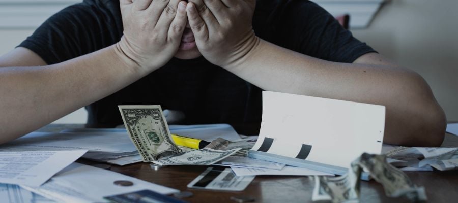 man distressed looking at money and bills